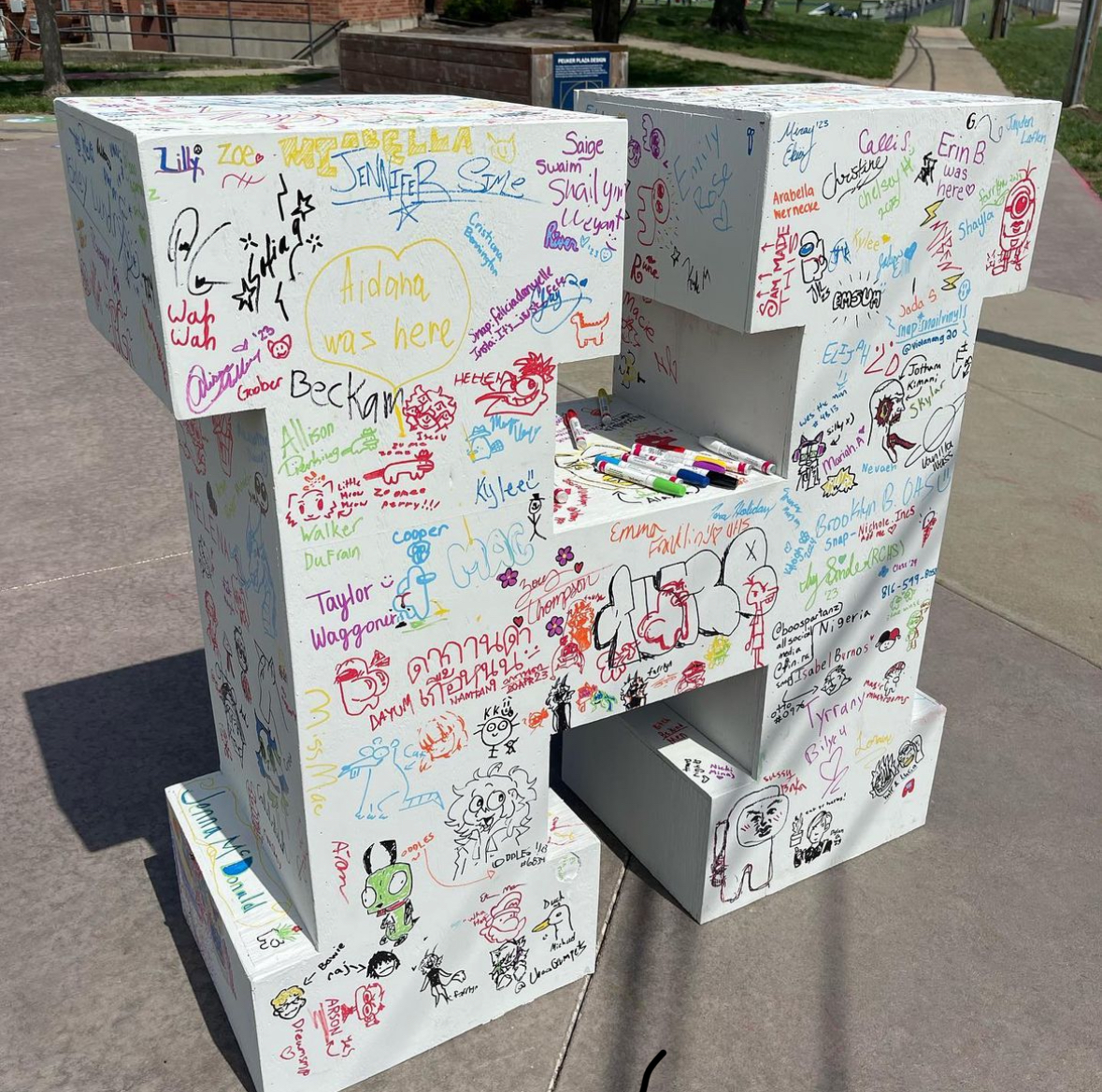 A large "H" sculpture with hundreds of signatures of little sketches all over it