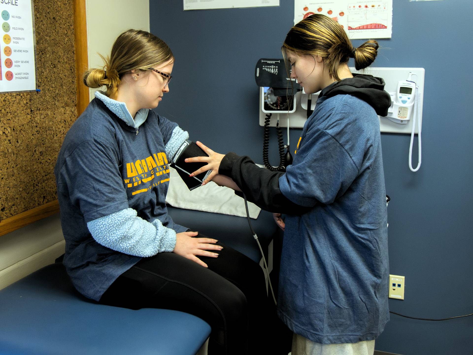 A medical assistant student takes blood pressure of another student.
