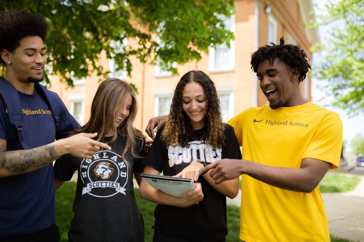 Group of students laughing as they review a notebook