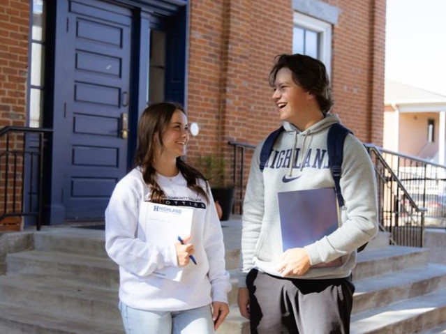 Two students are outside the front steps of Irvin Hall, looking at each other.