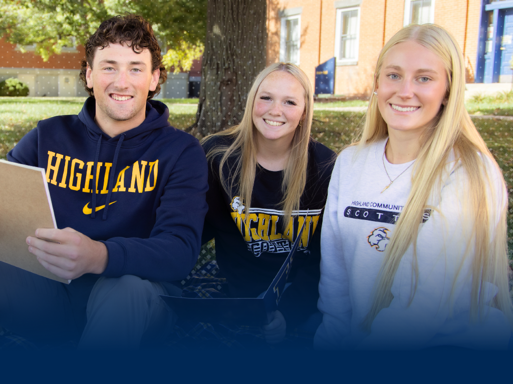 Three students pose together as they are sitting outside in the grass. Text reads "Summer Blitz"