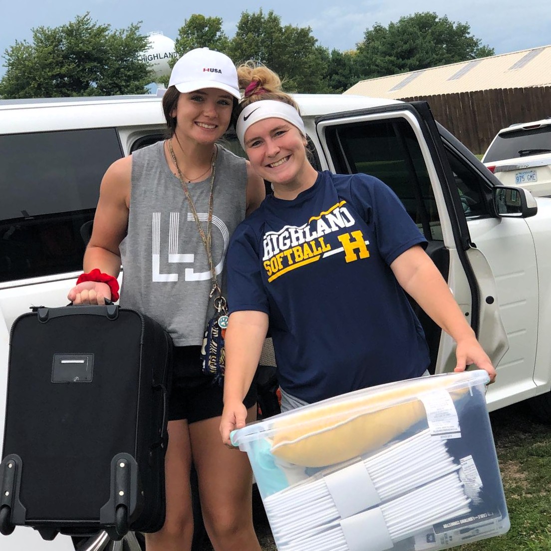 Two students carrying luggage on move in day